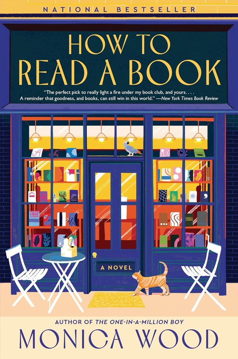 book cover for "how to read a book" by monica wood, featuring a colorful bookstore exterior with books in the window, two chairs, a table, and a cat lying on a mat.